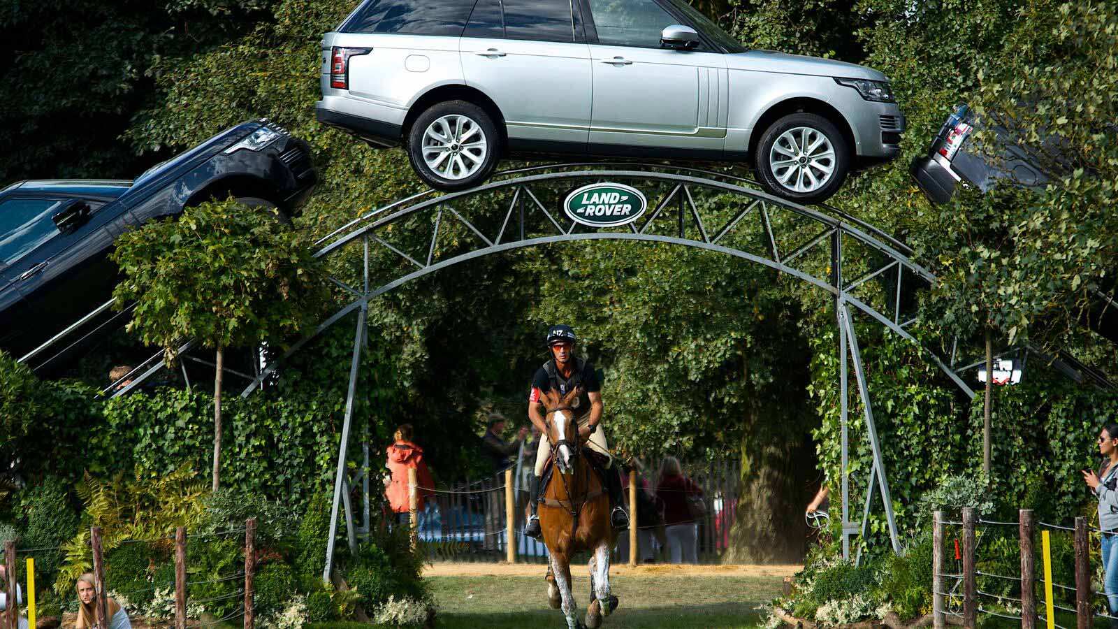 Equestrian rider under an archway of Land Rover vehicles.