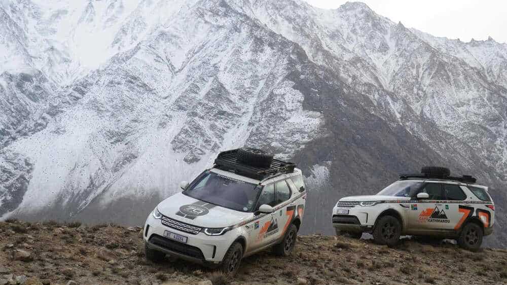 Land Rover Discovery cars with a mountain range in the background